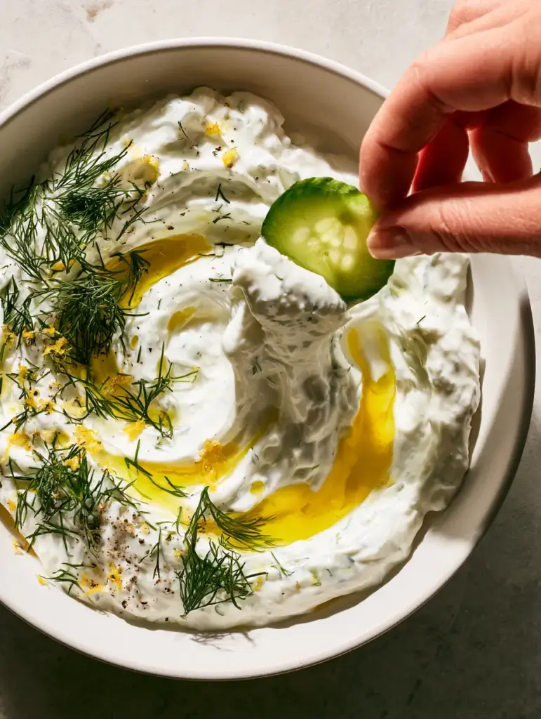 Cucumber Dip: The Ultimate Ultra-Thick Greek Tzatziki 1 Close-up of vibrant golden olive oil pooling in the thick ridges of a cucumber dip garnished with feathery dill and lemon zest.
