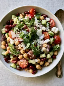 Close-up of glistening bean salad recipes with chickpeas, kidney beans, and fresh herbs in morning light. (bean salad recipes)