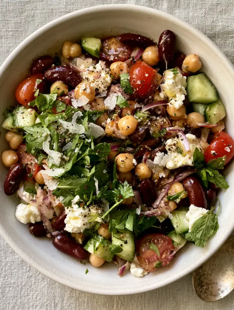 Mediterranean bean salad recipes with crumbled feta and fresh mint in a matte white bowl.