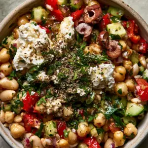 Close-up high-angle shot of a glossy Mediterranean bean salad with chickpeas, red peppers, and herb-flecked dressing. (Protein-Packed Dense Bean Salad)