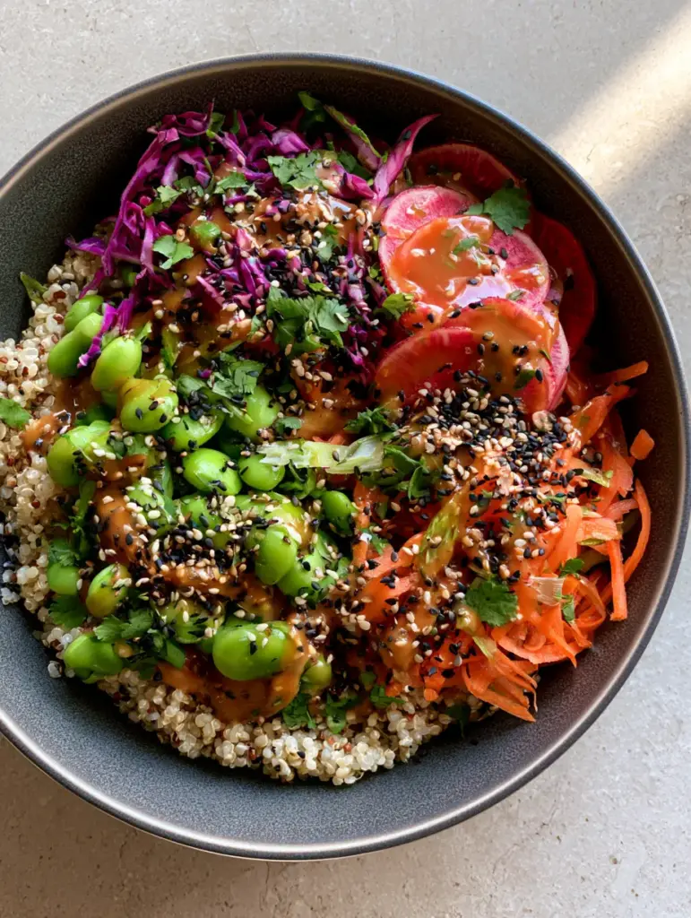 Close-up of glossy amber sesame ginger dressing coating an Edamame quinoa salad with toasted sesame seeds.