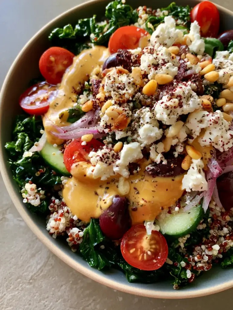 45-degree angle of a Quinoa kale salad topped with ribbons of thick golden tahini dressing, feta, and sumac.