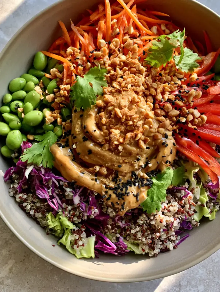 Close up of the thick creamy peanut dressing drizzled over a Thai quinoa salad with crushed peanuts and black sesame seeds.