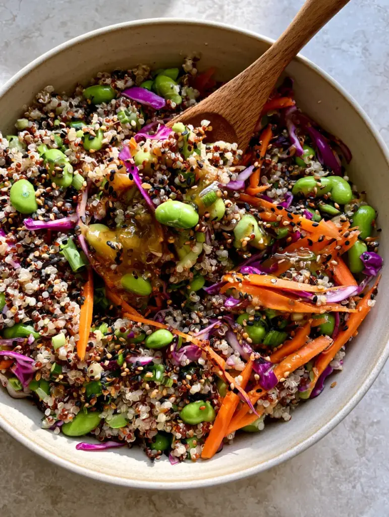Quinoa Edamame Salad with Ginger Soy Dressing (Vibrant & Protein-Packed) 1 Close-up of a wooden spoon lifting a portion of fluffy tri-color quinoa and bright green edamame.