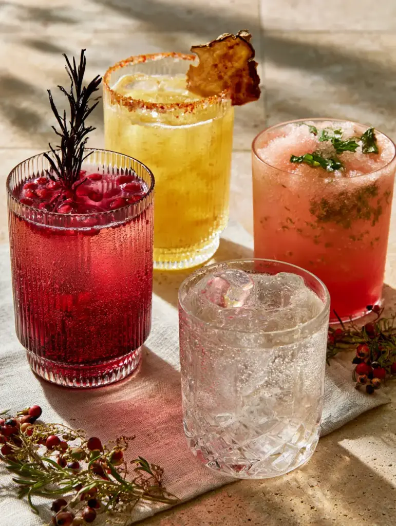 A bright golden pineapple ginger mocktail with a chili-salt rim and dehydrated pineapple slice in a crystal tumbler.