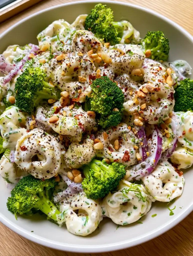 Tortellini Broccoli Salad with Zesty Herb Cream Dressing 2 Top-down view of a modern white bowl filled with Tortellini Broccoli Salad featuring zesty ivory dressing and fresh dill. (Tortellini Broccoli Salad)