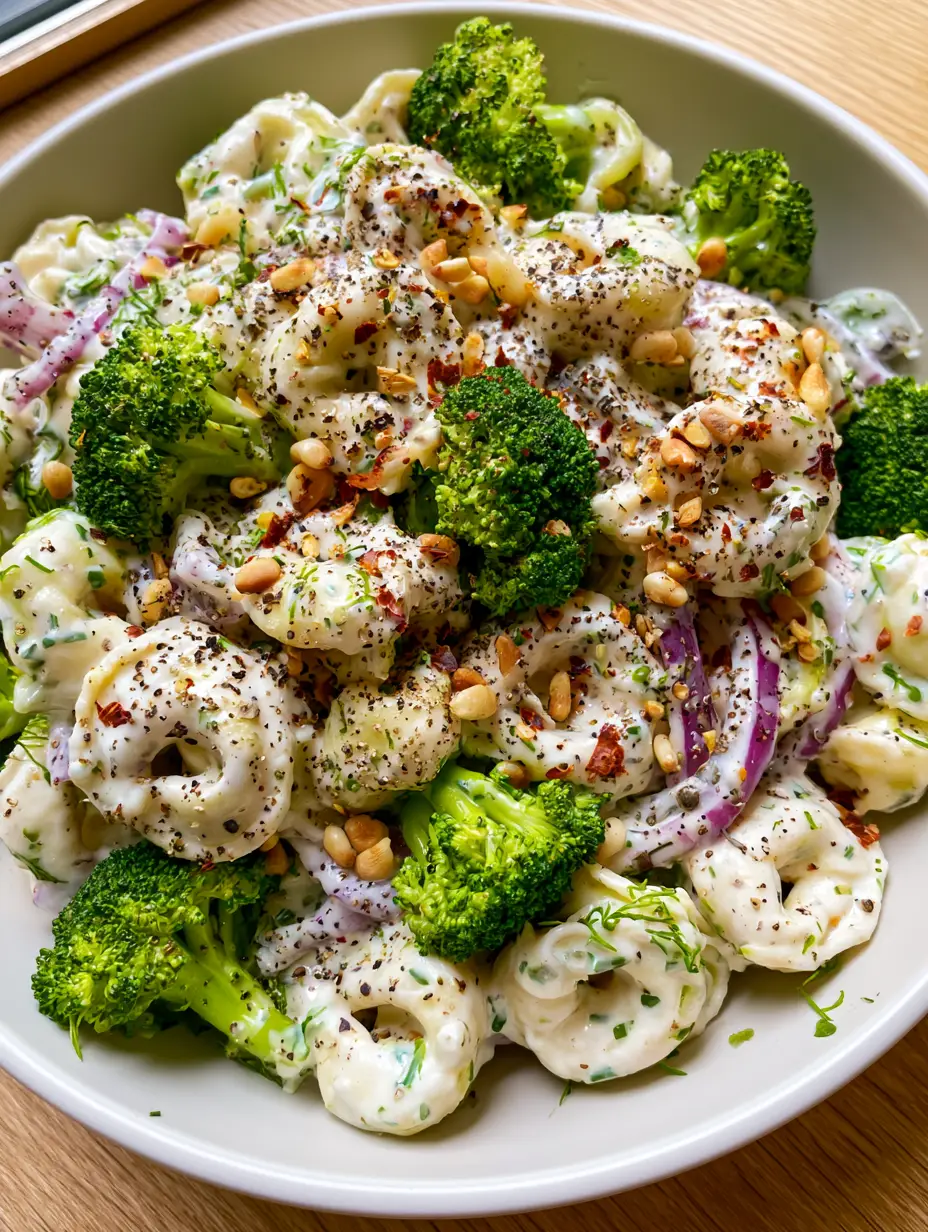 Tortellini Broccoli Salad with Zesty Herb Cream Dressing 3 Top-down view of a modern white bowl filled with Tortellini Broccoli Salad featuring zesty ivory dressing and fresh dill. (Tortellini Broccoli Salad)