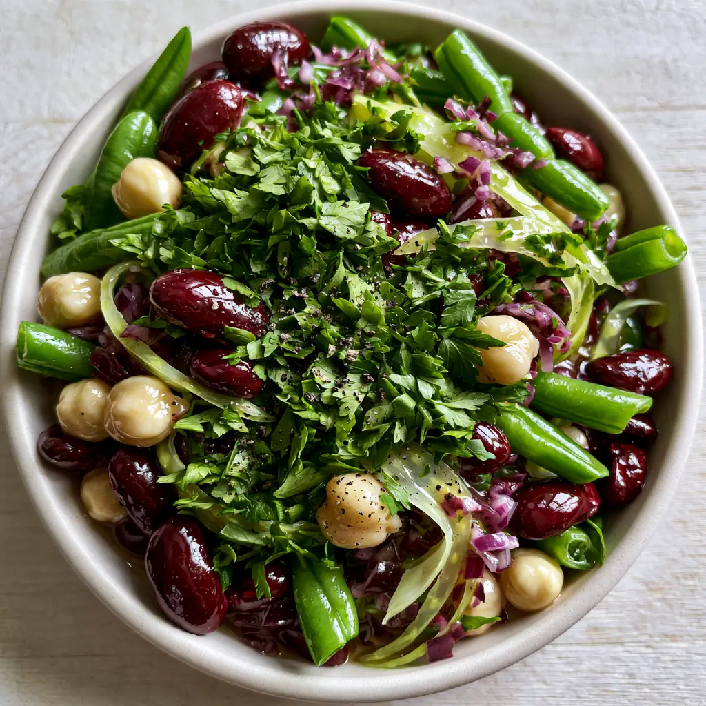 Close-up detail of the shimmering translucent sweet and sour dressing on a 3 bean salad with cracked black pepper.